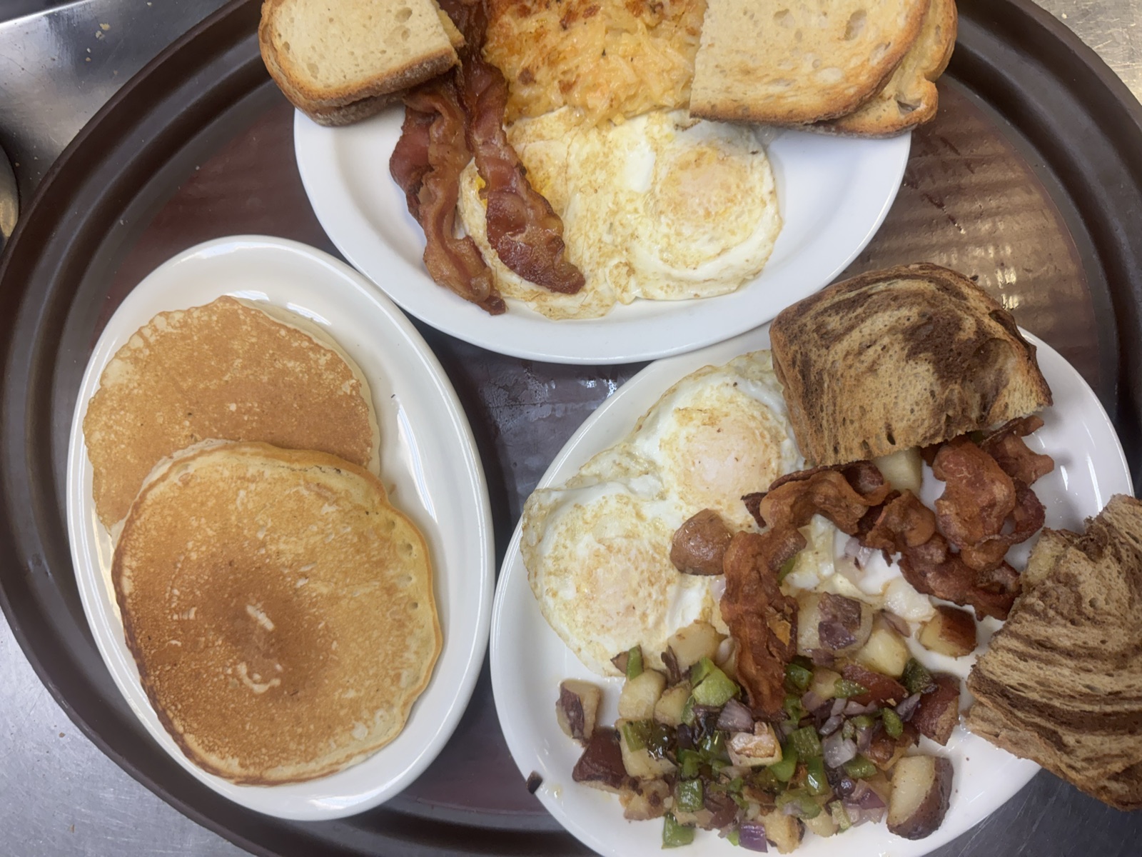 A breakfast plate with pancakes, eggs, and bacon